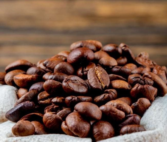 side view of brown coffee beans in a sack on rustic background side view of brown coffee beans in a sack on rustic background